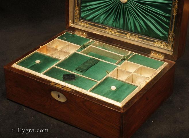 Ref:  SB625: Rosewood sewing box with mother of pearl oval inlaid to the top and rounded edges  retaining its original  compartmentalized tray with supplementary lids in green satin silk. There is a document wallet in the lid.  This has ruched green satin silk framed with gold embossed leather.  The box has a working lock with key, Circa 1850  Enlarge Picture